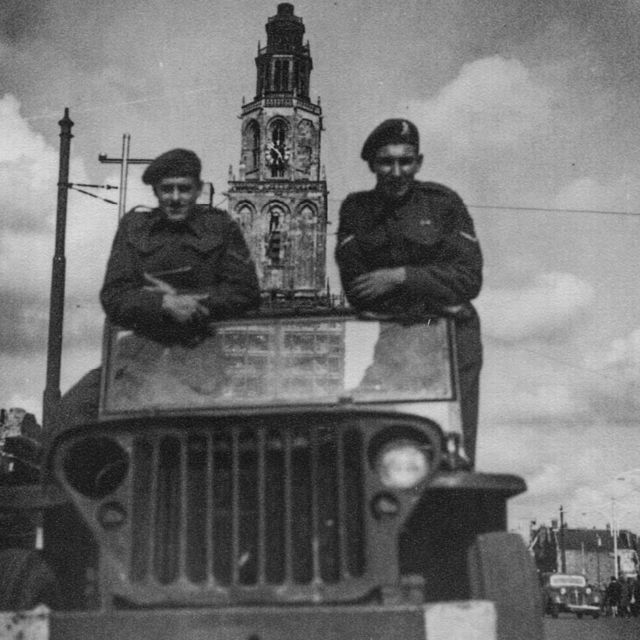 Twee Canadese militairen poseren in hun jeep op de Grote Markt voor de Martinitoren. 